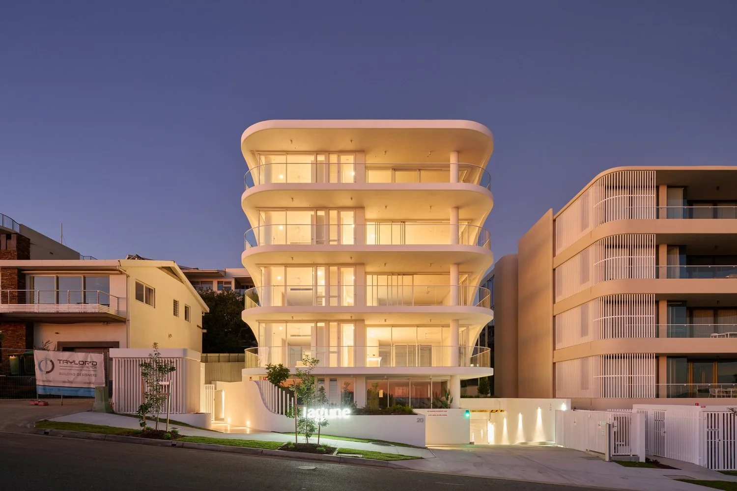 Lagune’s curved balconies and illuminated apartments at dusk, Moffat Beach