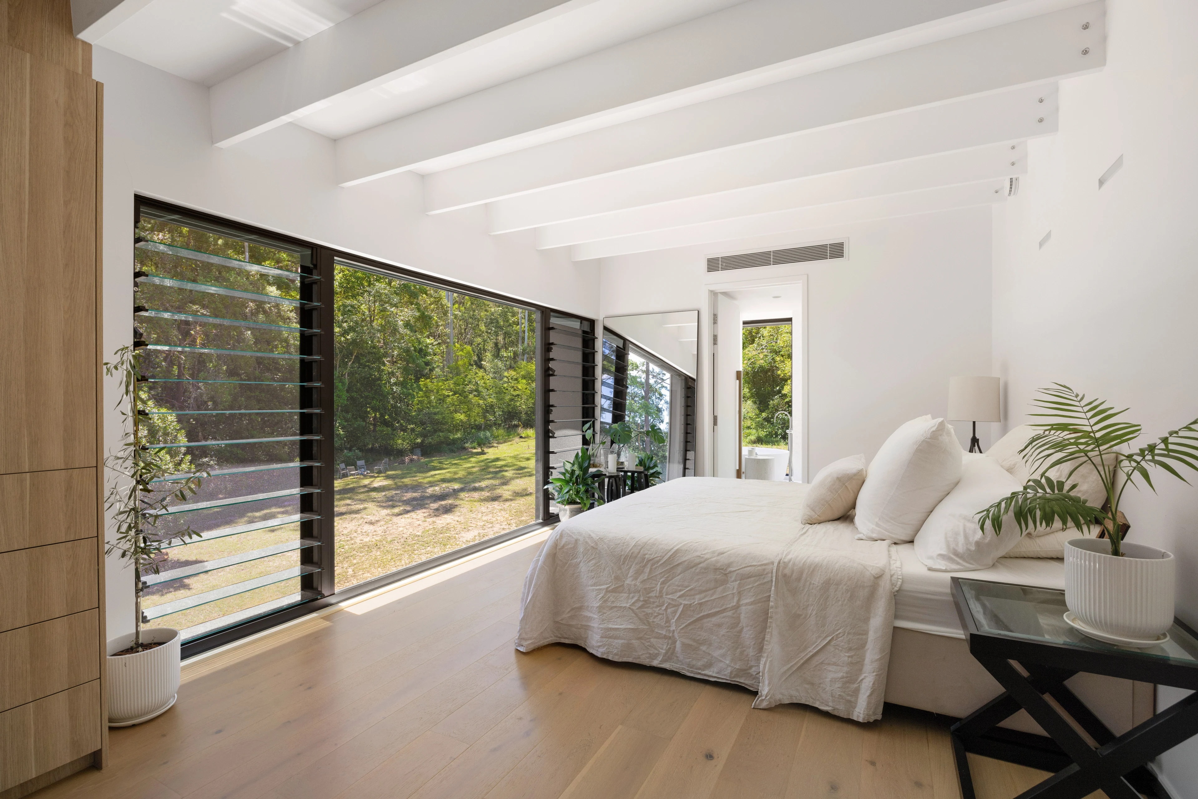 De Wald Haus bedroom framed by garden views and exposed white beams
