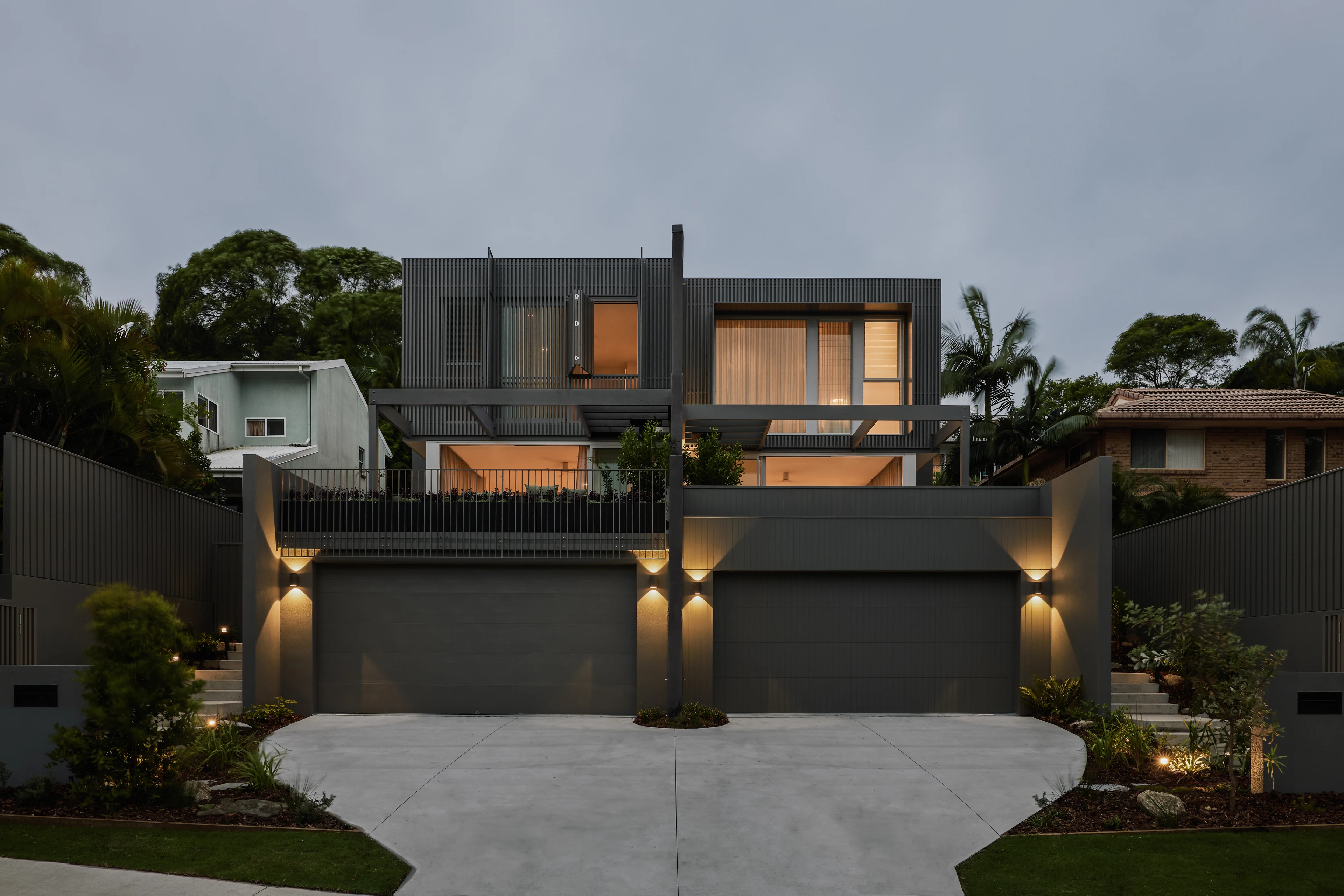 Palmera — completed residences with illuminated timber screens at dusk