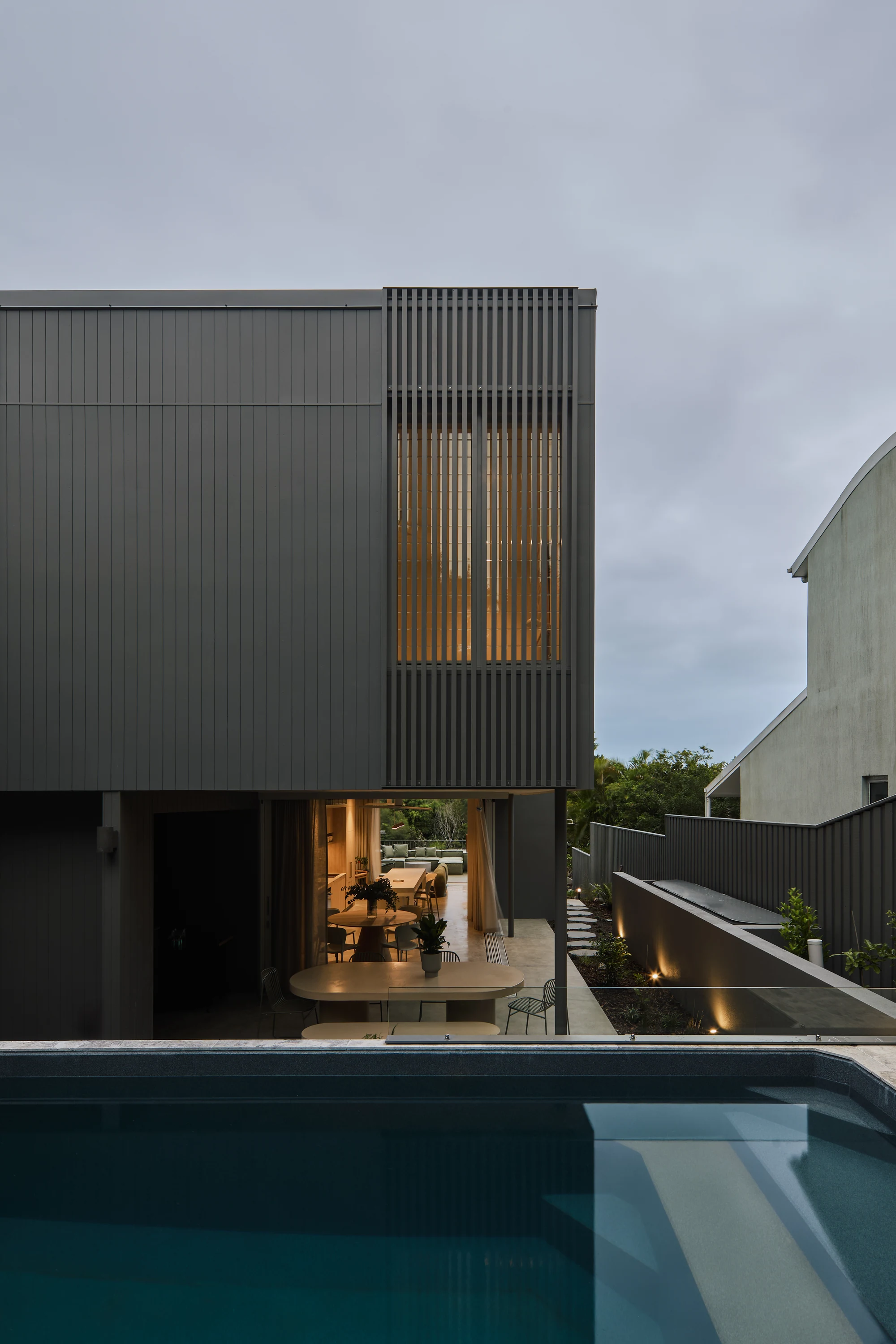 Palmera timber facade screens above the pool at dusk