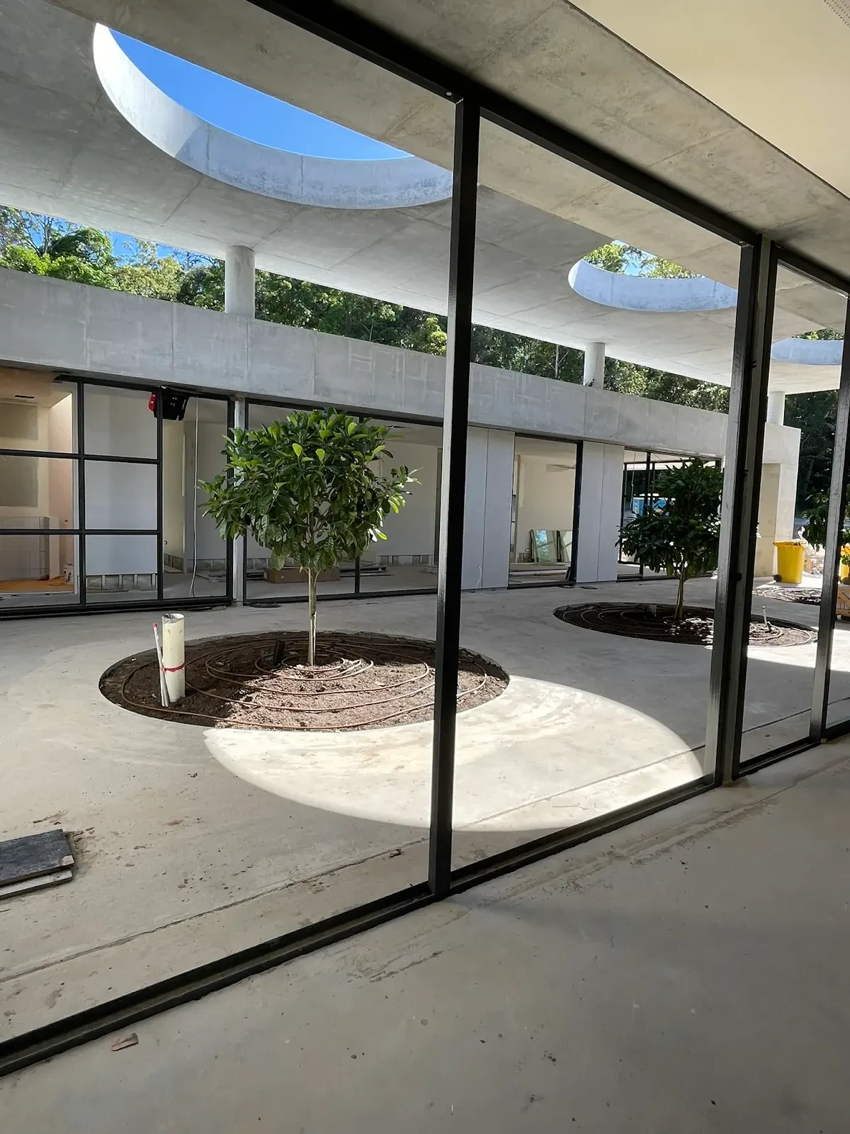 The Villa courtyard and circular roof openings seen through installed glazing