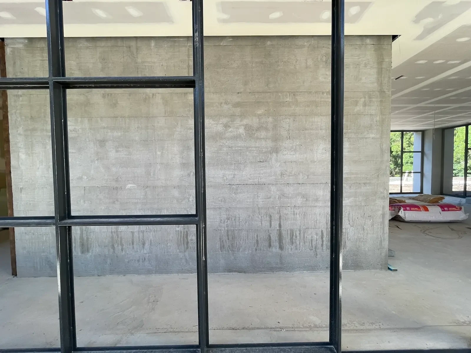 Black glazing frames meeting exposed concrete walls at The Villa