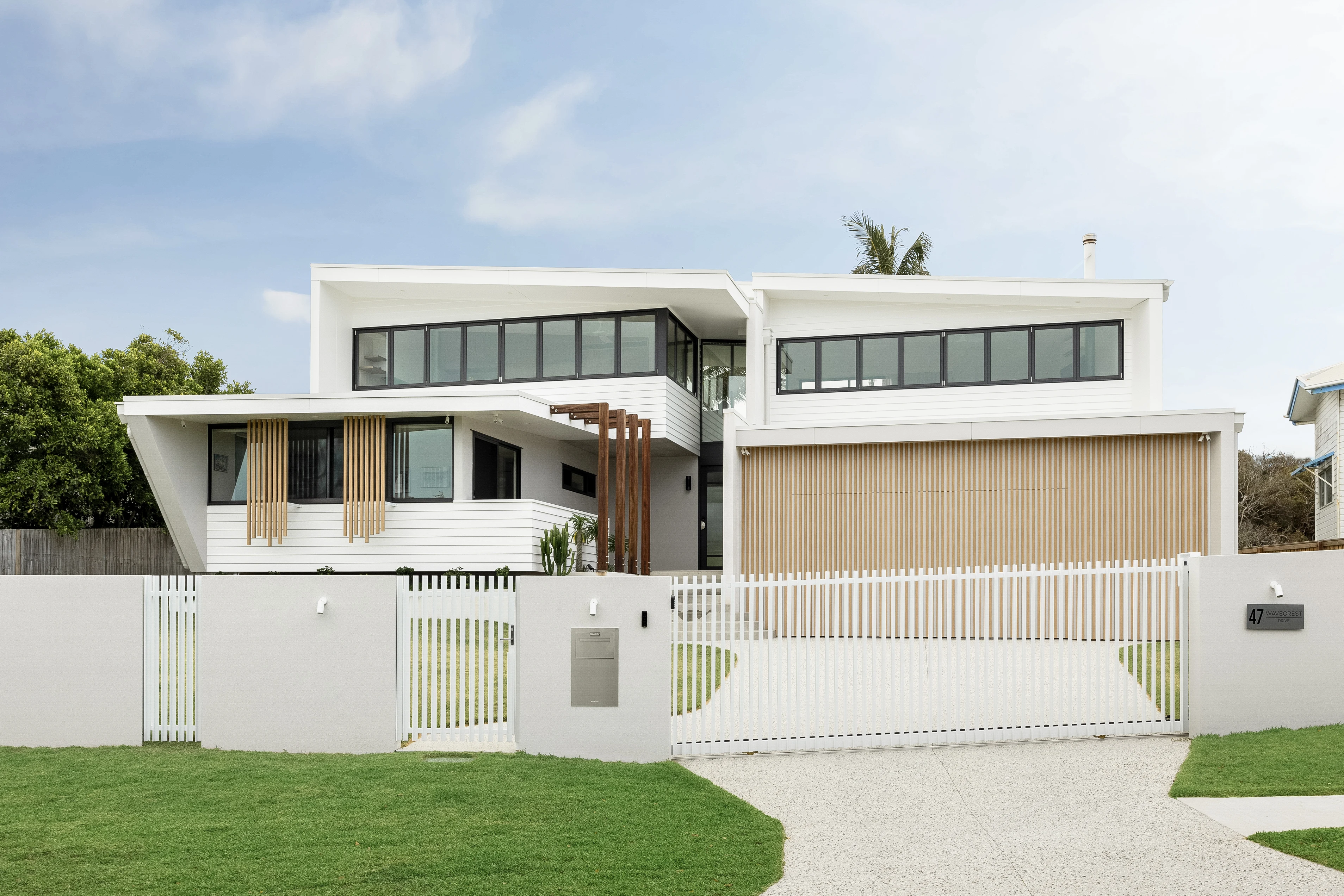 47 Wavecrest, a white coastal home with timber screens and a landscaped entrance