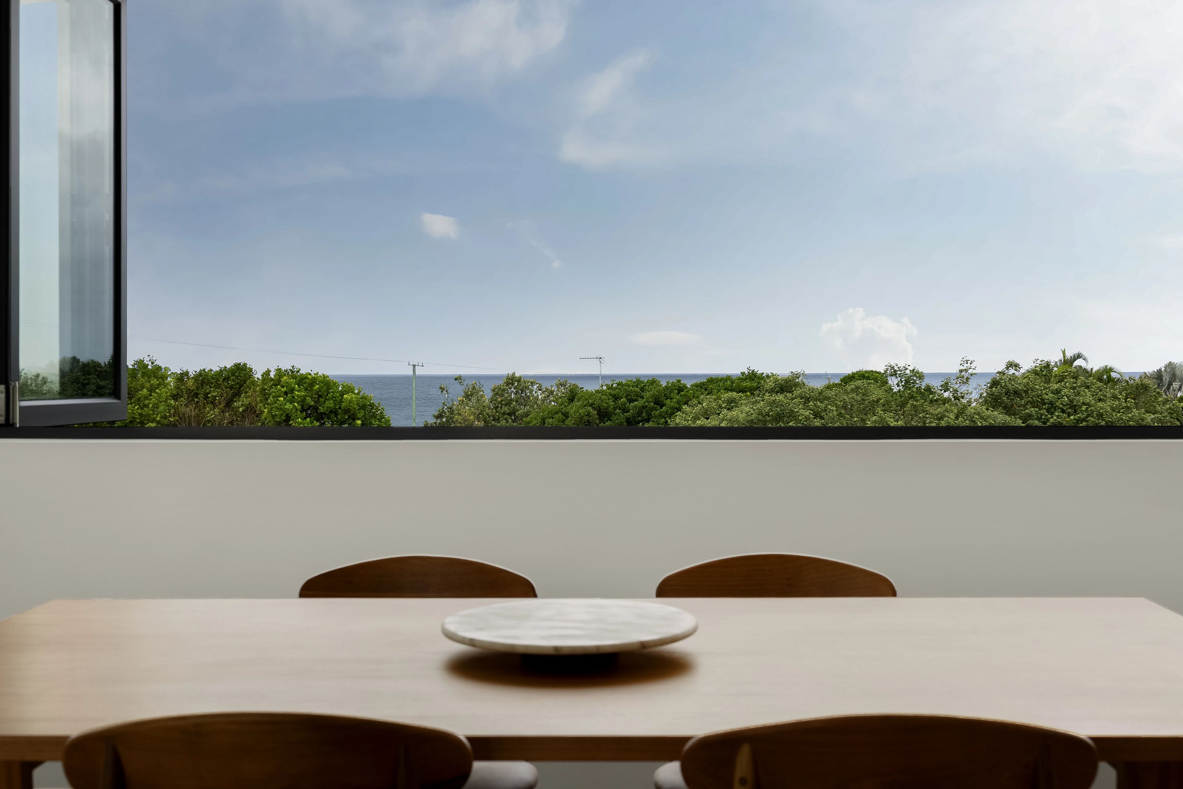 Dining table overlooking trees and the ocean horizon