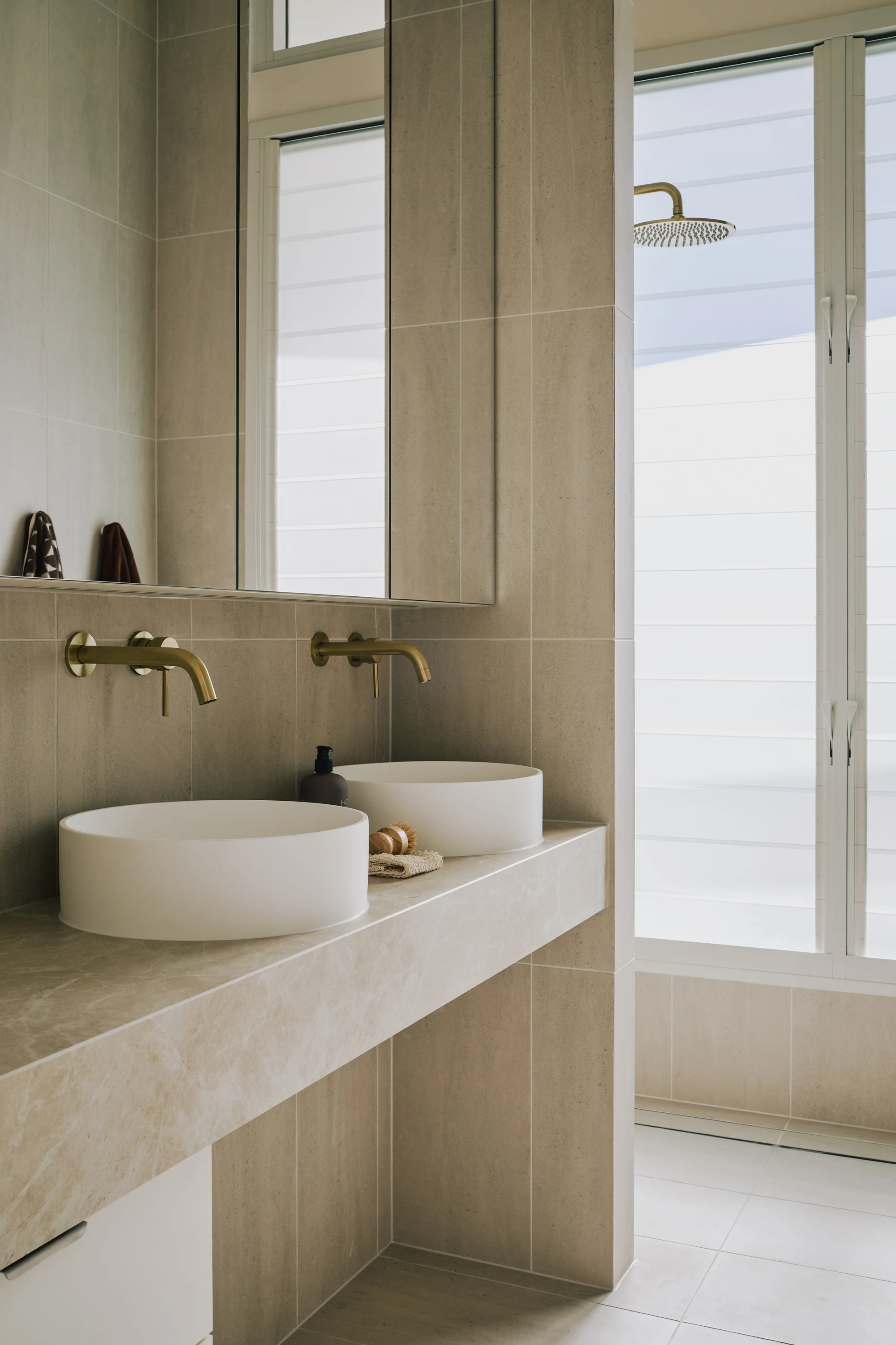 Pale stone vanity with twin basins and brass fixtures
