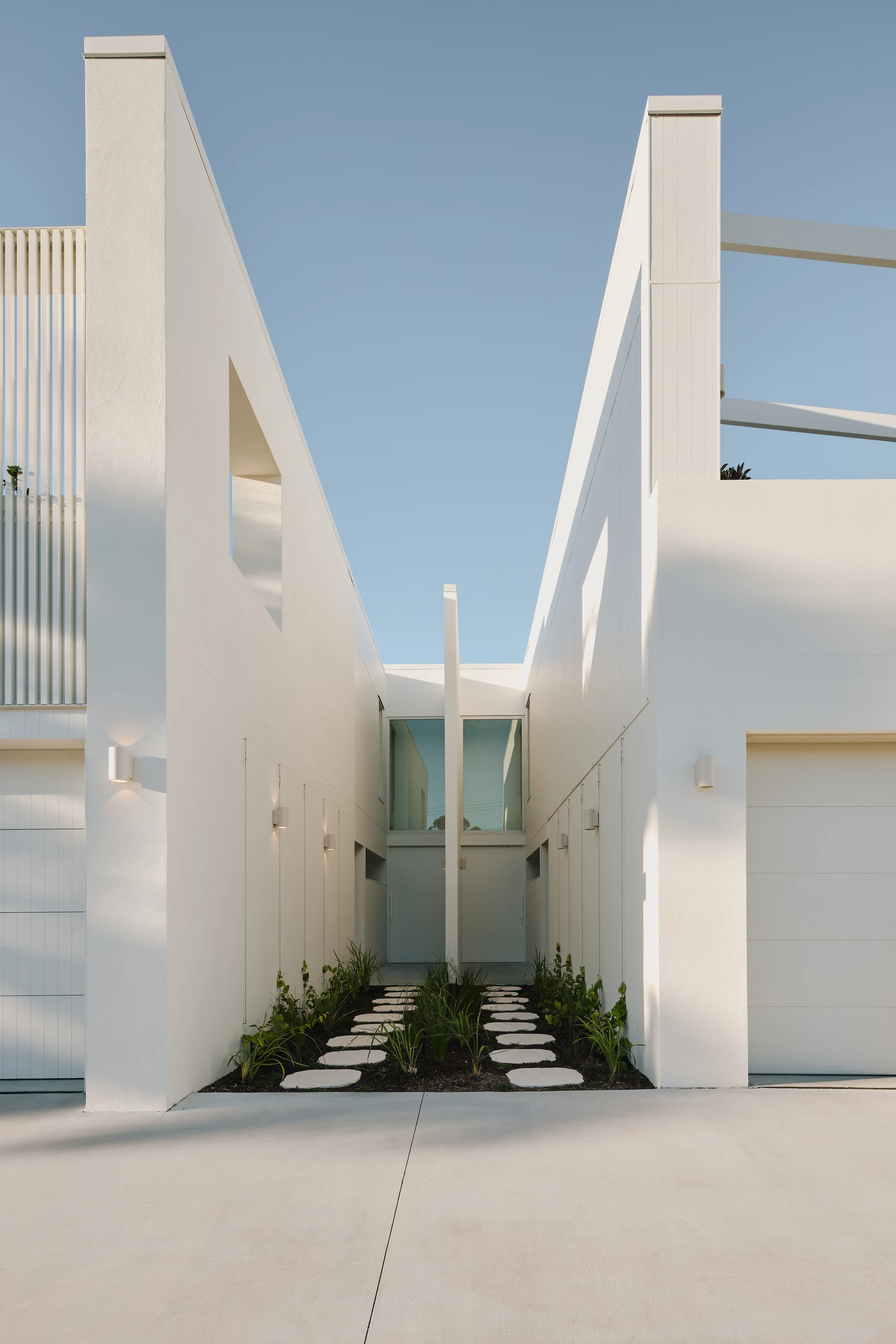 Sculpted white entry walls and planted pathway