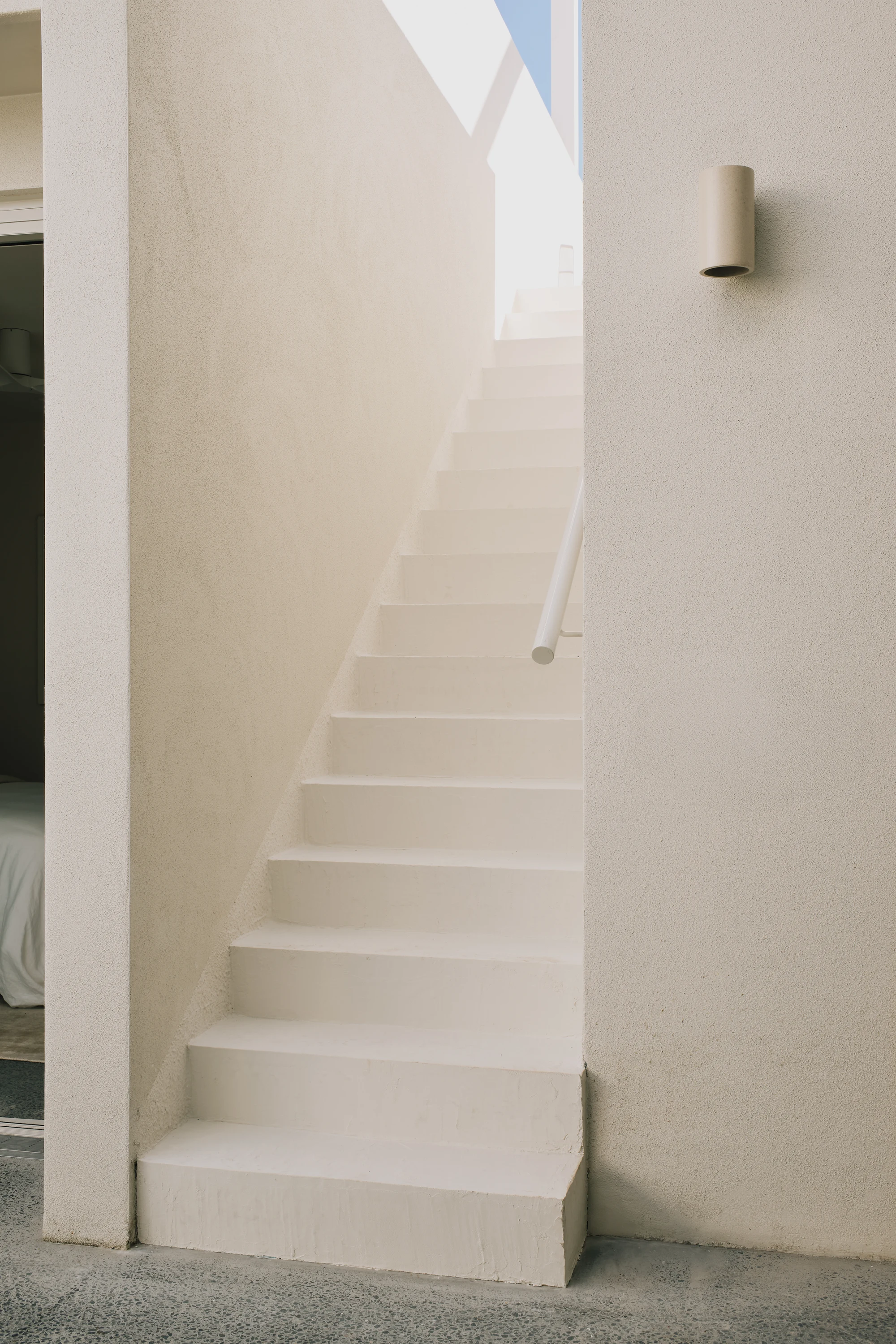 White staircase beneath a tall sunlit void